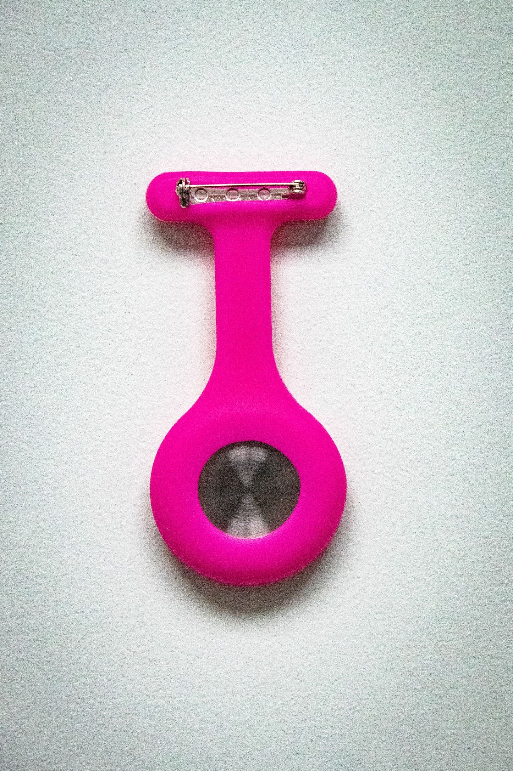 Rear view of the RMIT Store magenta fob watch, featuring a smooth magenta silicone casing and metal pin clasp attachment.